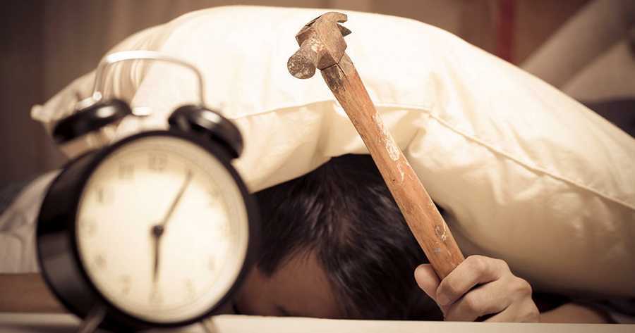 Personne qui a du mal à se réveiller et qui essaie de casser son horloge.Difficulté à se réveiller le matin peut être causé par le stress.