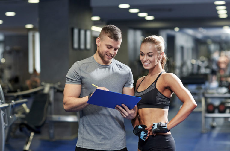 Coach sportif avec un programme mude musculation à la main. Il donne des informations à son élève.