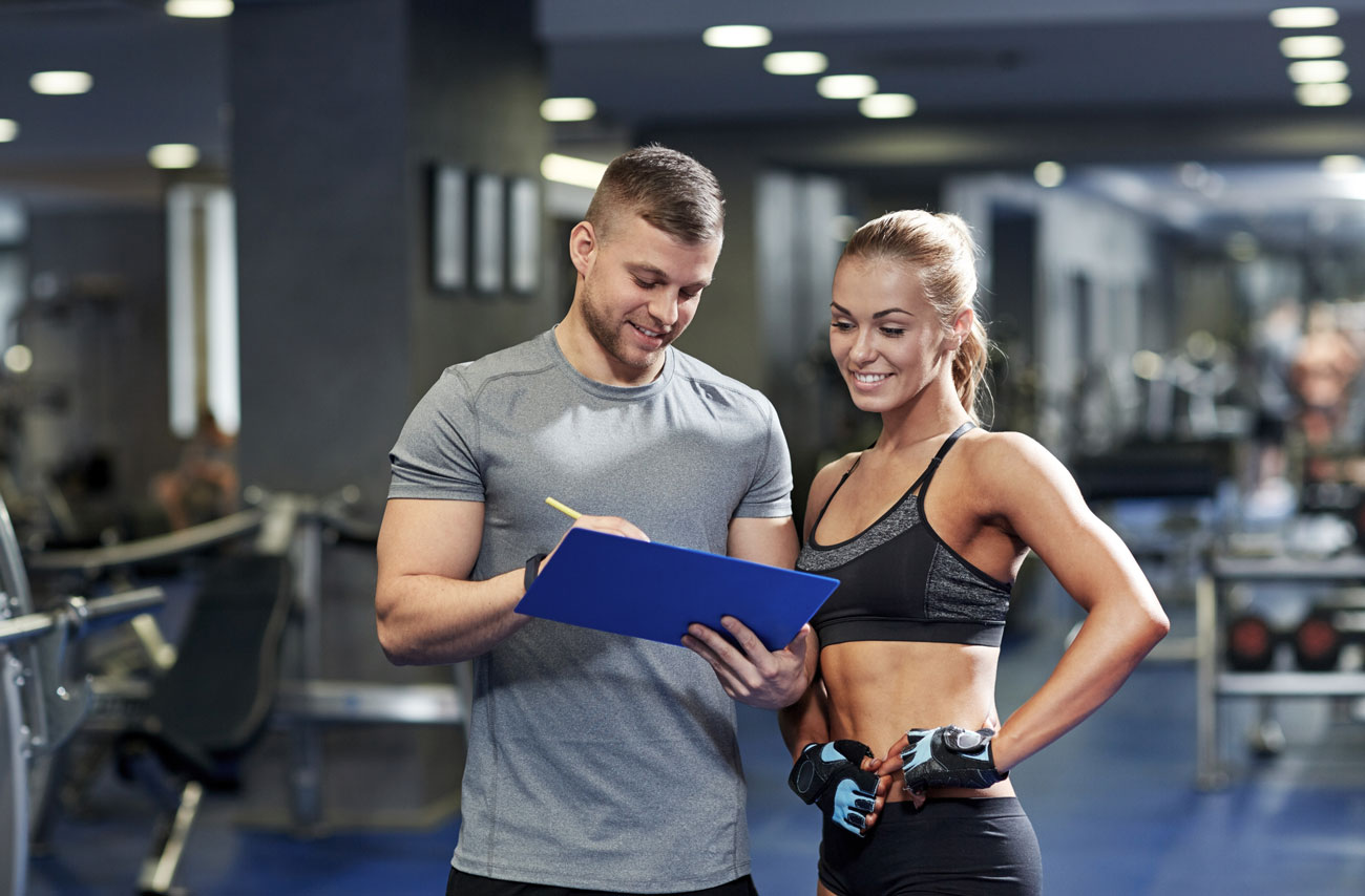 Coach sportif avec un programme mude musculation à la main. Il donne des informations à son élève.