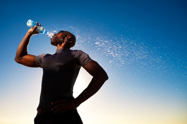 sportif qui boit une bouteille d'eau dans sa récupération.